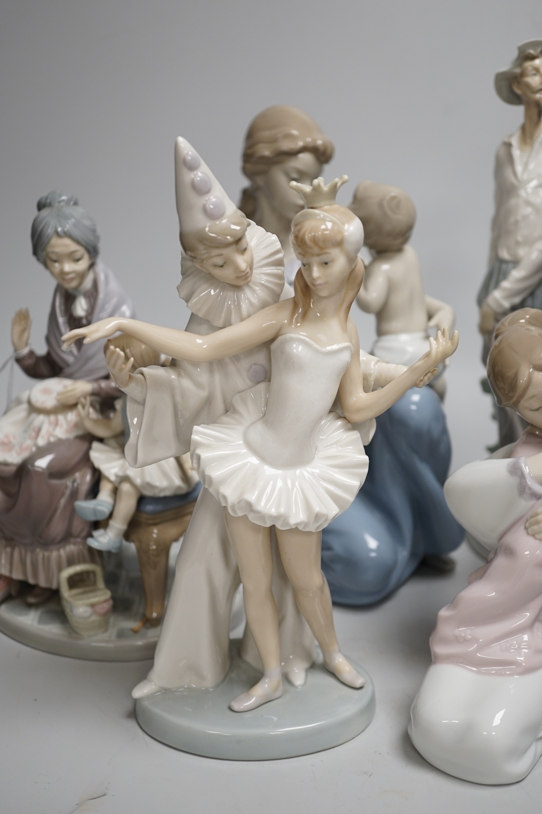 A large Lladro figure of a seated mother and child, a pierrot and ballerina, peasant woman and child, a grandmother and child and two others including a Nao example, the largest 30cm high (6)
